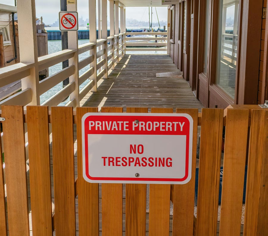 Wooden gate with a private property no trespassing sign in an outdoor setting.