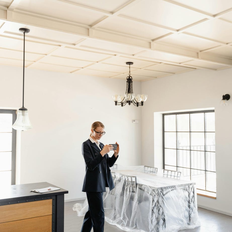 A real estate agent photographs the interior of a modern unfurnished home.